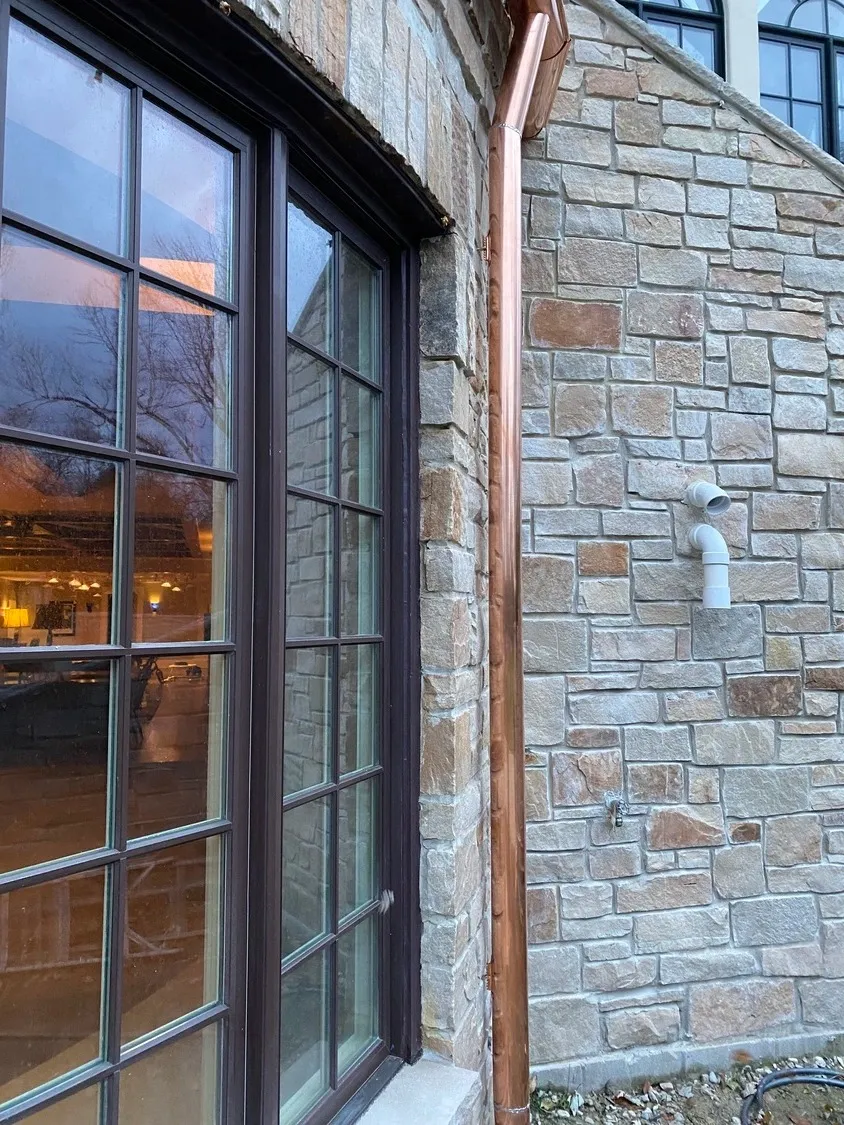 Copper downspout detail on stone facade