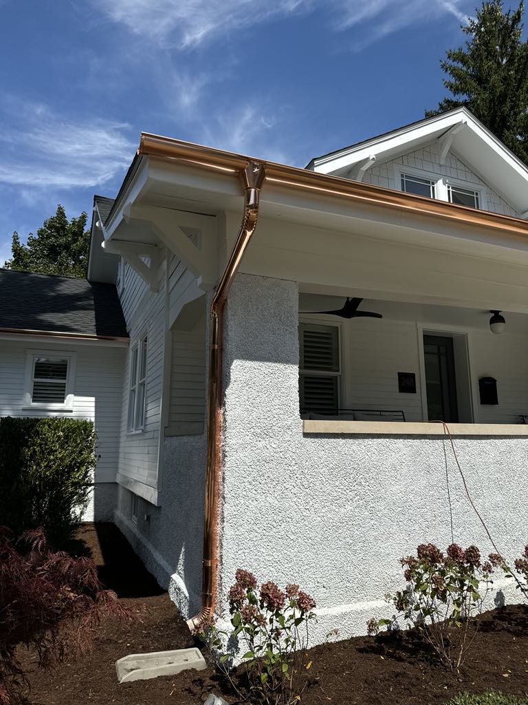 Copper gutters and downspout on white craftsman home
