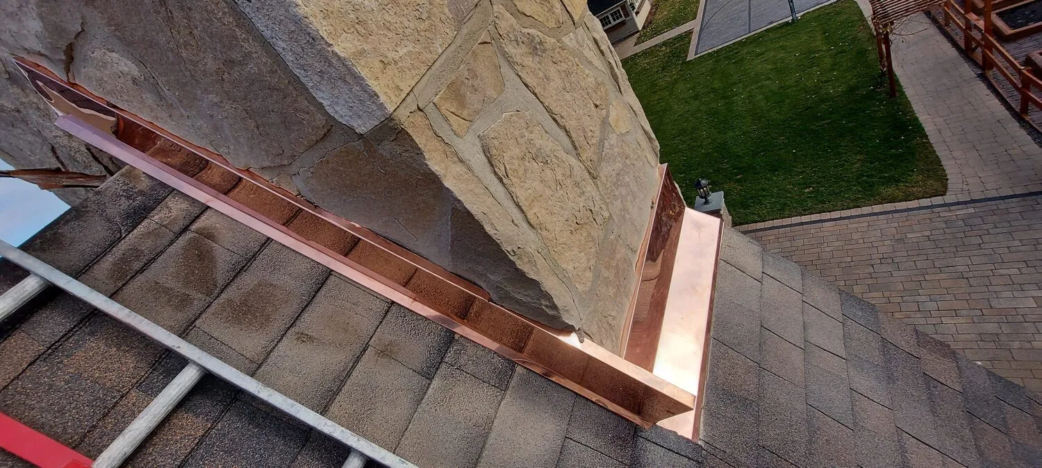 Custom copper chimney flashing on shingle roof